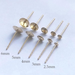 May include: An assortment of gold-coloured earring posts in different sizes, from 2.5mm to 6mm. Each post has a flat, circular disc and a thin, straight post for insertion. Sizes are labelled in millimetres.