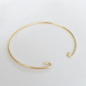Pode incluir: Um bracelete simples de ouro com fecho de gancho.