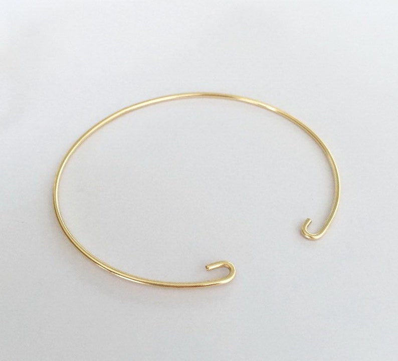 Op de afbeelding: Een eenvoudige gouden armband met een haaksluiting.