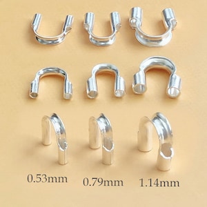 Puede incluir: Nueve anillos de metal plateado de diferentes tamaños, con medidas en milímetros: 0,53 mm, 0,79 mm y 1,14 mm. Los anillos están dispuestos en tres filas, con tres anillos en cada fila.