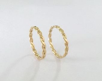May include: Two gold braided rings, one slightly larger than the other, on a white background.