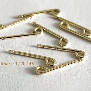 Puede incluir: Seis hallazgos de pendientes de metal dorado con un bucle en un extremo y un extremo pequeño, plano y redondo en el otro. Los hallazgos están marcados con "1/20 14K".