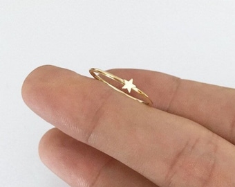 May include: A delicate gold ring with a small star charm. The ring is thin and simple, making it a perfect everyday accessory.