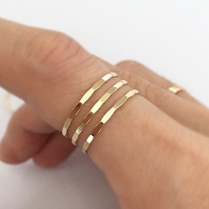 Puede incluir: Cuatro anillos apilables de oro con textura martillada. Los anillos se llevan en un dedo.