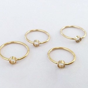 Puede incluir: Cuatro anillos de oro con una abertura redonda en el centro. Los anillos son de diferentes tamaños y tienen una textura ligeramente martillada.