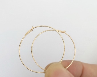 Puede incluir: Un par de pendientes de aro de oro con un acabado texturizado.