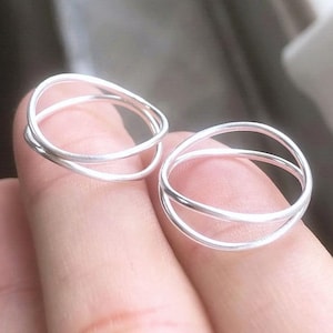 May include: Two silver rings with a simple, modern design. The rings are intertwined, creating a unique and stylish look.