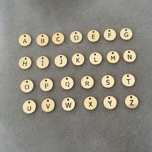 Puede incluir: Un conjunto de 26 abalorios de letras del alfabeto de metal dorado. Cada abalorio es un círculo con una sola letra grabada. Las letras están en orden alfabético de la A a la Z.