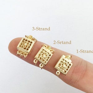 Puede incluir: Tres cierres de metal dorado para collares o pulseras. Los cierres son de forma cuadrada con un diseño intrincado y tienen diferentes números de bucles para sujetar múltiples hebras de joyería. Los cierres están etiquetados como "3-Strand", "2-Strand" y "1-Strand".