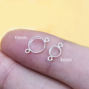 Könnte beinhalten: Zwei silberne Zargenfassungen für die Schmuckherstellung. Die größere Fassung hat einen Durchmesser von 6 mm und die kleinere einen Durchmesser von 4 mm.