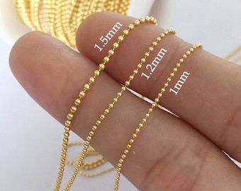 May include: Three gold chains of different sizes, 1 mm, 1.2 mm, and 1.5 mm, are shown on a finger. The chains are made of small, round beads.