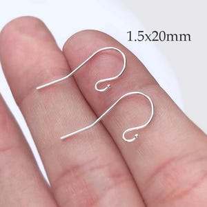 May include: Two silver earring hooks, each with a curved design and a small ball at the end. The text "1.5x20mm" is visible, indicating the size of the hooks. The hooks measure 1.5mm x 20mm.