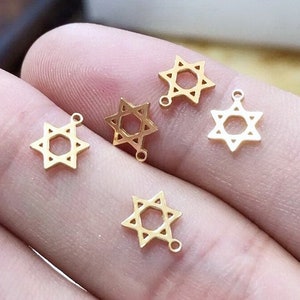 Puede incluir: Cinco amuletos de metal de color dorado en forma de estrella de seis puntas, también conocida como la Estrella de David.