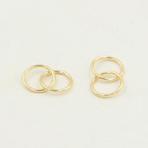 Könnte beinhalten: Zwei Sätze goldfarbener ineinandergreifender Ringe. Jeder Satz besteht aus zwei Ringen, wobei der eine etwas größer ist als der andere.