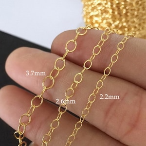 May include: Three gold chains of different sizes, 3.7 mm, 2.6 mm, and 2.2 mm, are shown laid out on a hand. The chains are made of small, round links.