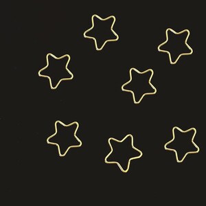 May include: Seven gold star-shaped metal hoops on a black background.