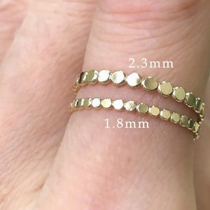 May include: Two gold rings with a beaded design. The top ring has beads that are 2.3 mm in diameter, and the bottom ring has beads that are 1.8 mm in diameter.
