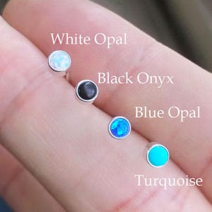 May include: Four small stud earrings with different gemstones: white opal, black onyx, blue opal, and turquoise. Each earring has a silver setting. The names of the gemstones are written above each earring.
