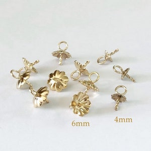 May include: Gold-toned metal bead caps with a flower-shaped design. The caps have a small loop at the top and a pointed end at the bottom. The caps are available in two sizes: 4mm and 6mm.