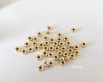 May include: A pile of small, gold-colored metal jump rings, each measuring 3 mm in diameter.