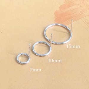 Op de afbeelding: Drie zilveren oorringen in verschillende maten. De kleinste oorring heeft een diameter van 7 mm, de middelste oorring heeft een diameter van 10 mm en de grootste oorring heeft een diameter van 15 mm.