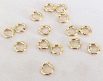 May include: A collection of 14 gold jump rings, perfect for jewelry making or crafting projects.