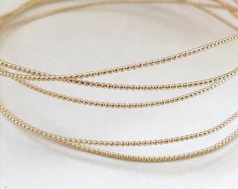 May include: Five strands of gold bead wire, each strand is a continuous circle of small gold beads.
