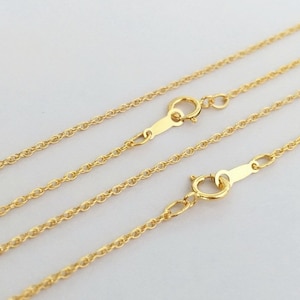 May include: Two gold chains with lobster clasps. The chains are layered on top of each other.