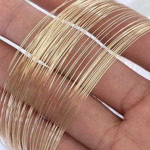 May include: A close-up of a bundle of gold-coloured wire. The wire is thin and flexible, and it is arranged in a neat stack.