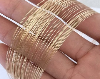 May include: A close-up of a bundle of gold-coloured wire. The wire is thin and flexible, and it is arranged in a neat stack.