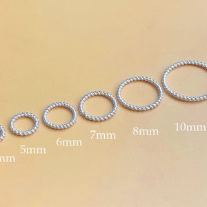 May include: A set of seven silver twisted hoop earrings in various sizes, ranging from 4mm to 10mm. The earrings are arranged in order of size, with the smallest on the left and the largest on the right.