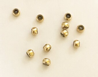 May include: A group of 12 gold-colored metal beads with a hole in the center. The beads are scattered on a white surface.