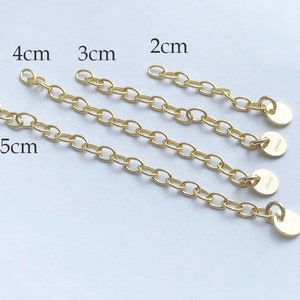 May include: Four gold chain extenders with different lengths: 2 cm, 3 cm, 4 cm, and 5 cm. Each extender has a small round disc at the end.