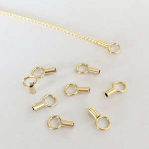 May include: Gold-toned metal chain with multiple gold-toned metal end caps with a small loop at one end and a small cylinder at the other end.