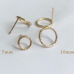 Op de afbeelding: Twee paar gouden cirkelvormige oorbel studs. Het kleinere paar heeft een diameter van 7 mm en het grotere paar heeft een diameter van 10 mm.