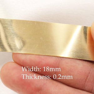 May include: A close-up of a gold-coloured metal strip. The text on the image reads: Width: 18mm, Thickness: 0.2mm. The strip is held by a person's fingers.