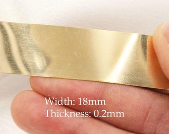 May include: A close-up of a gold-colored metal strip. The text on the image reads: Width: 18mm, Thickness: 0.2mm. The strip is held by a person's fingers.