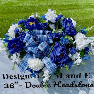 May include: A blue and white floral arrangement with a plaid bow, designed for a 36-inch double headstone. The arrangement includes blue and white flowers, greenery, and a plaid bow.