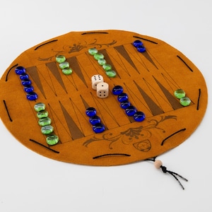May include: A brown leather backgammon game set with green and blue glass playing pieces and two white dice. The game is rolled up and has a black drawstring.