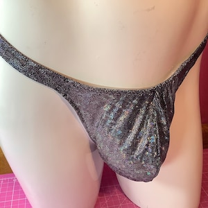 Puede incluir: Un tanga negro y plateado brillante con un corte de talle bajo.