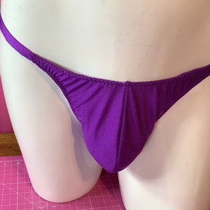 Puede incluir: Tanga de color morado con tirantes finos. La ropa interior está hecha de una tela suave y sedosa.