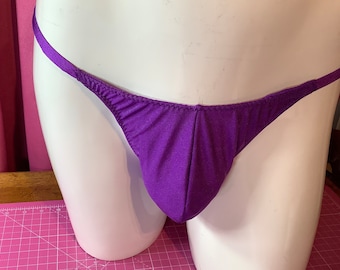 May include: Purple thong underwear with thin straps. The underwear is made of a smooth, silky fabric.