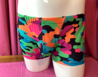 Puede incluir: Bañador negro con un estampado de camuflaje abstracto de colores en tonos de rosa, naranja, verde y azul.