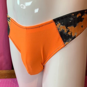 Puede incluir: Ropa interior de color naranja y negro con un patrón y una costura negra alrededor de los bordes.