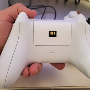 May include: A white wireless Xbox controller with a black connector on the back.