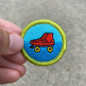 May include: A blue and green embroidered patch with a red roller skate with yellow wheels. The patch has a white border.