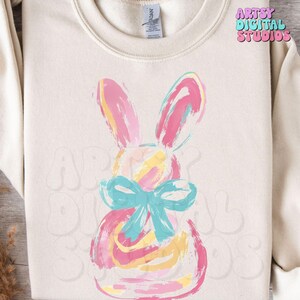 May include: A colorful, abstract painting of an Easter bunny with a blue bow. The bunny is painted in shades of pink, yellow, and blue.