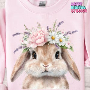 May include: A pink sweatshirt with a watercolor illustration of a brown bunny wearing a flower crown. The crown is made of pink, white, and purple flowers.
