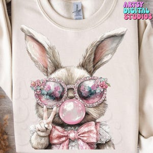 May include: A brown bunny wearing pink sunglasses with rhinestones and a pink bow. The bunny is blowing a pink bubble and giving a peace sign.