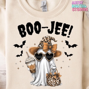 May include: Cream-colored sweatshirt with a Halloween-themed graphic. The design features a ghost wearing heart-shaped sunglasses, a leopard print hat and bow, and holding a coffee. The text "BOO-JEE!" is above the ghost, with bats and stars around it.